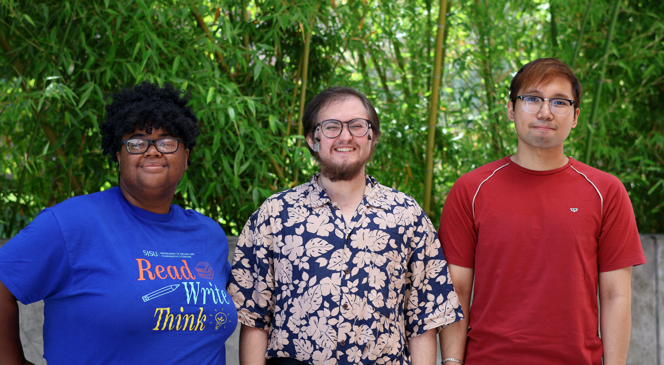 Three writing tutors facing camera and standing in front of bamboo background