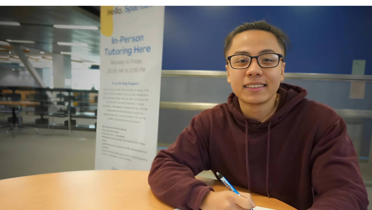 Writing tutor seated at round table holding pen and writing